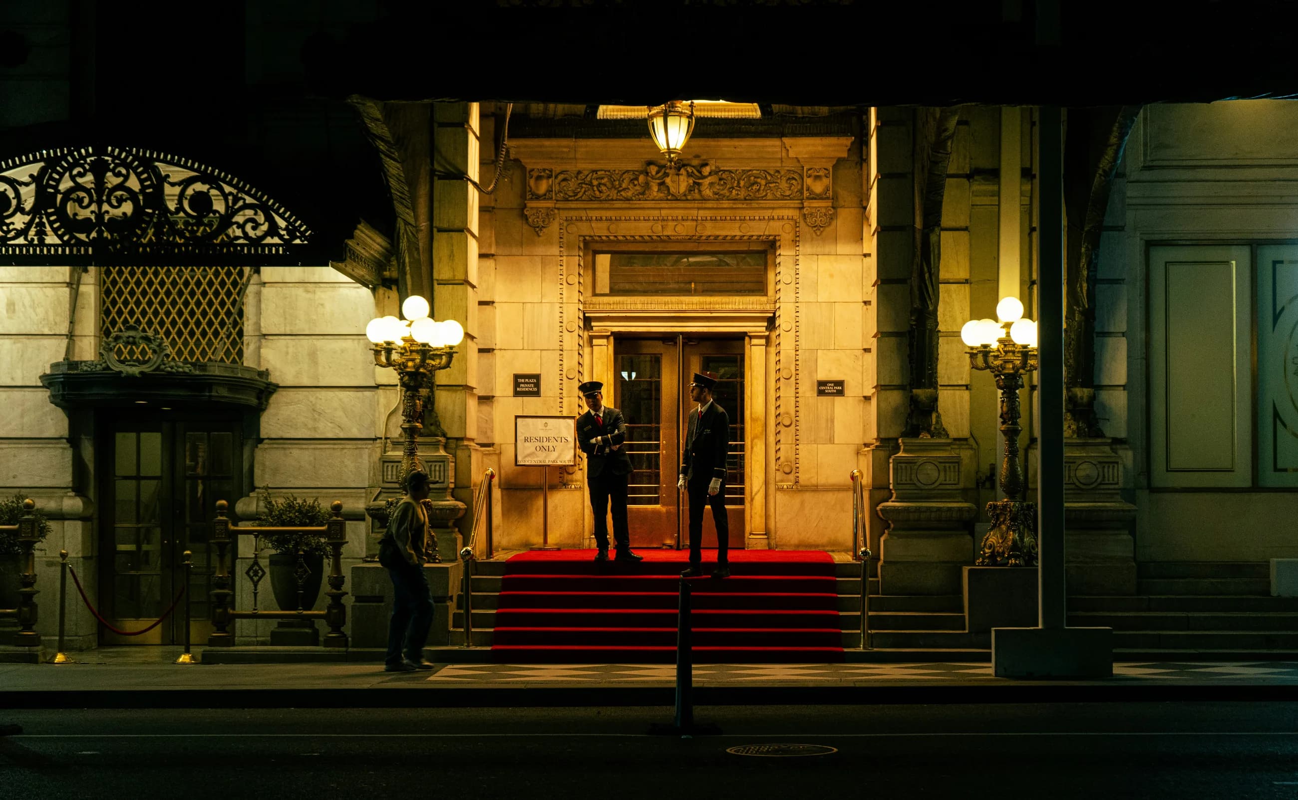 The entrance of a grand hotel at night, doormen on the red carpet