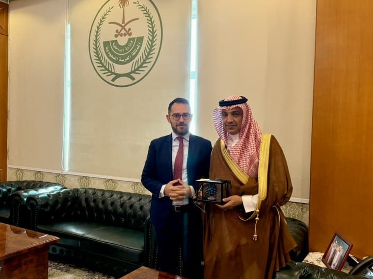 Kledis Brahimi accanto a un funzionario saudita in abito tradizionale durante uno scambio di doni, sotto lo stemma del Ministero dell'Interno