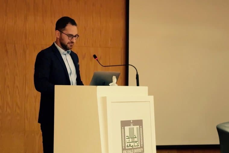 Kledis Brahimi a un leggio con lo stemma della King Khalid University